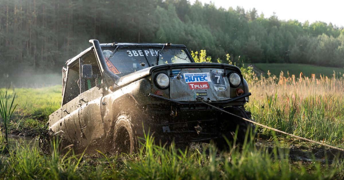 A rugged off-road vehicle plowing through muddy fields during a daytime adventure.