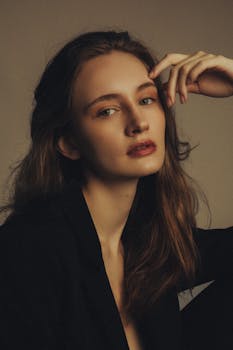 A striking portrait of a young woman with long hair in a soft, moody studio setting.