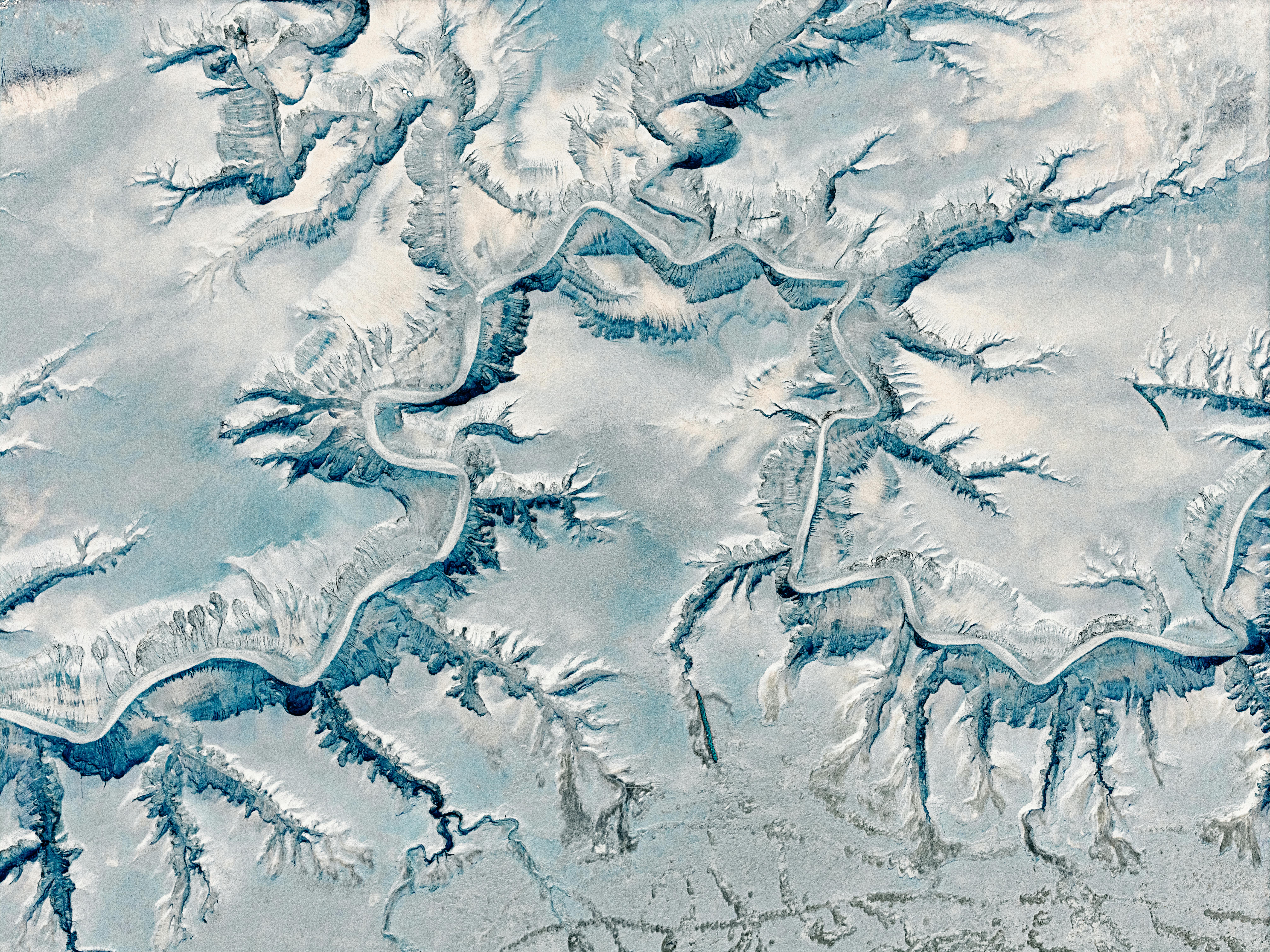 A stunning aerial view of a winding snow-covered canyon with intricate geological formations.