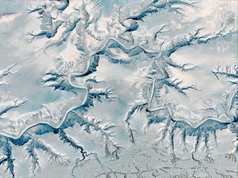 A stunning aerial view of a winding snow-covered canyon with intricate geological formations.