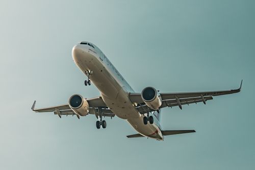 Free A commercial airplane descends for landing, showcasing its undercarriage and engines against a blue sky. Stock Photo