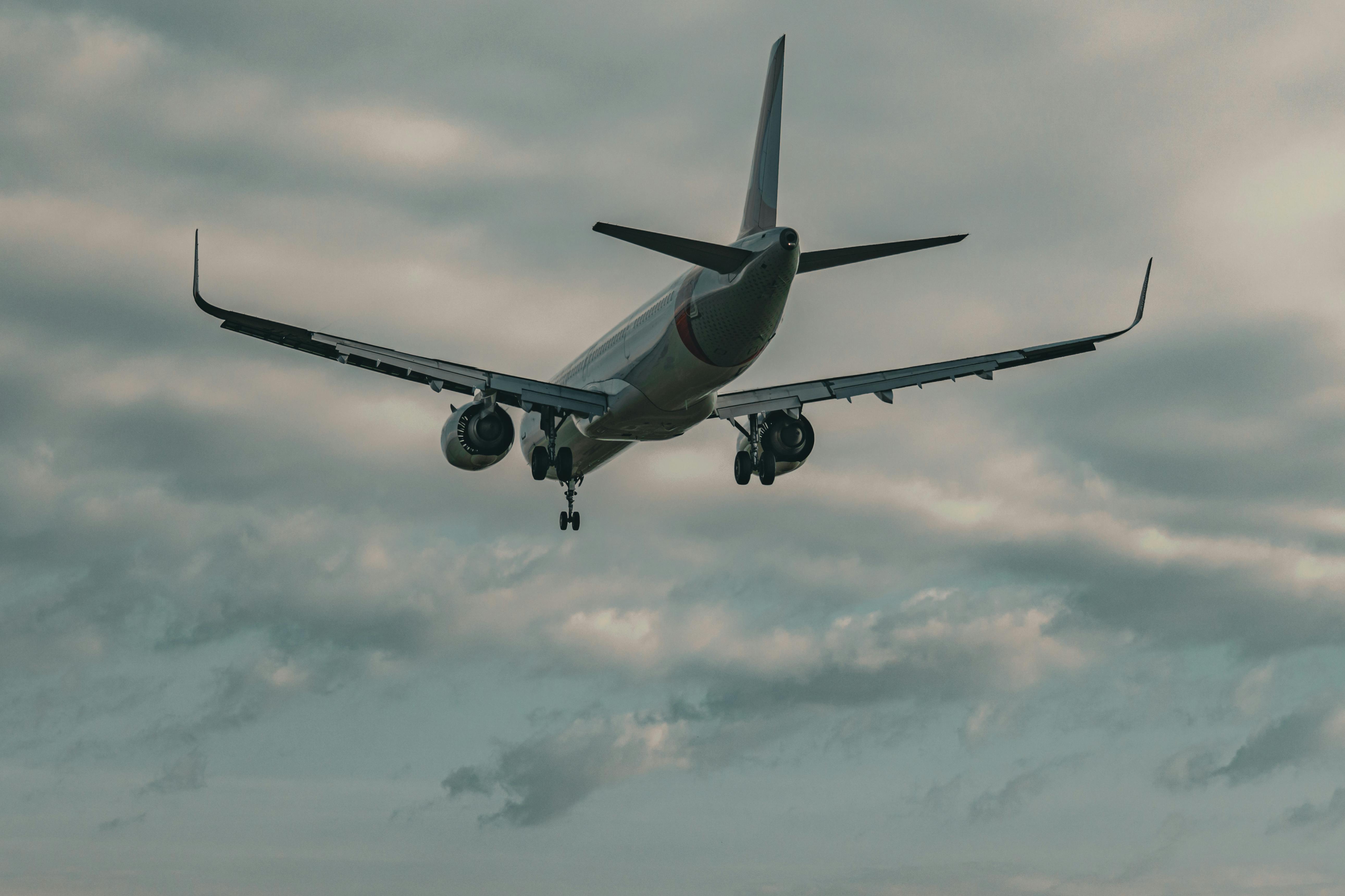 A commercial airplane approaches for landing under overcast skies, showcasing aviation and travel themes.