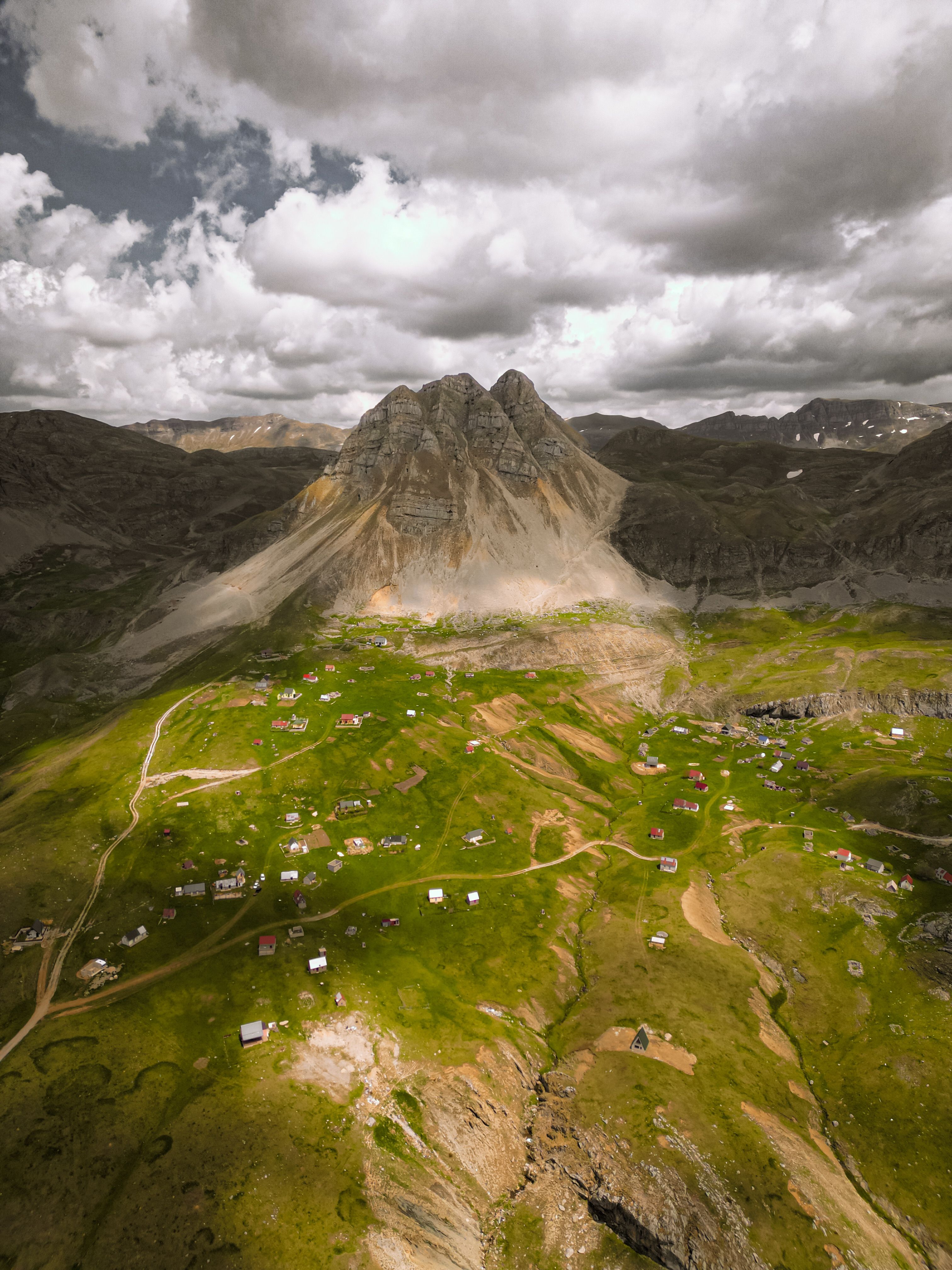 Stunning aerial view capturing lush valleys and majestic mountain peak with scattered houses.