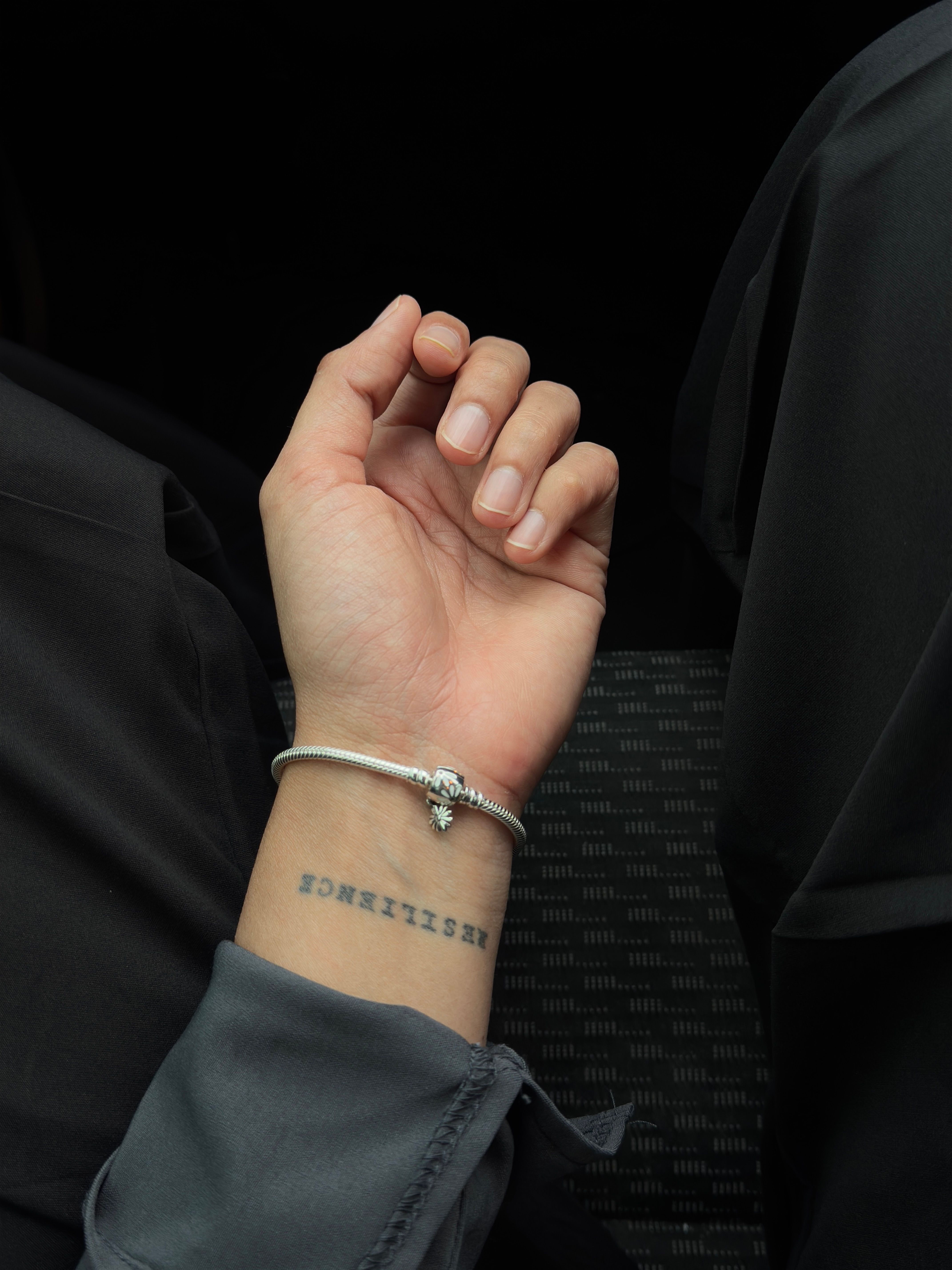 Minimalist custom temporary tattoo design worn on the wrist with a bracelet, everyday lifestyle setting