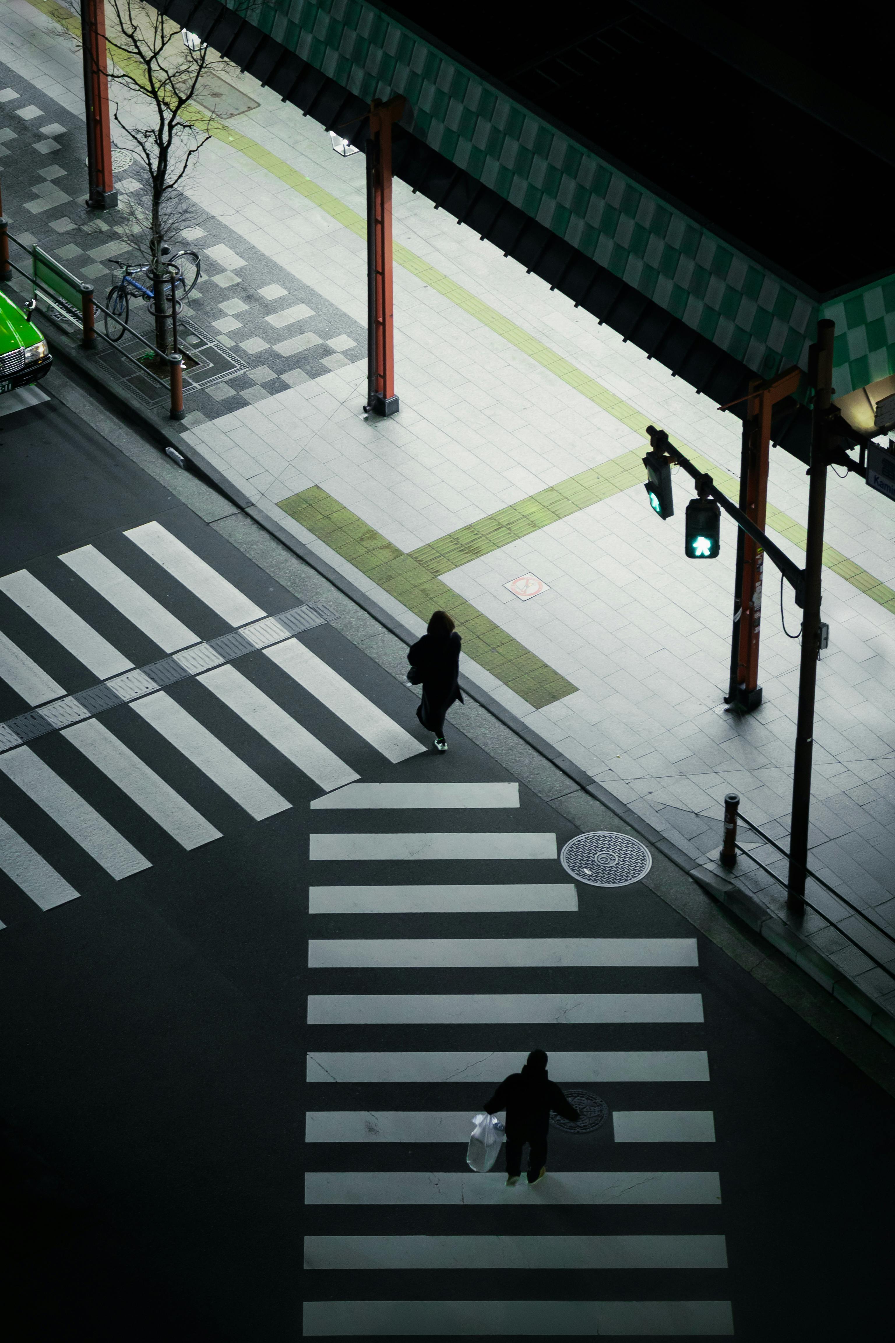 Aerial view of pedestrians crossing a zebra crossing in Tokyo at night.