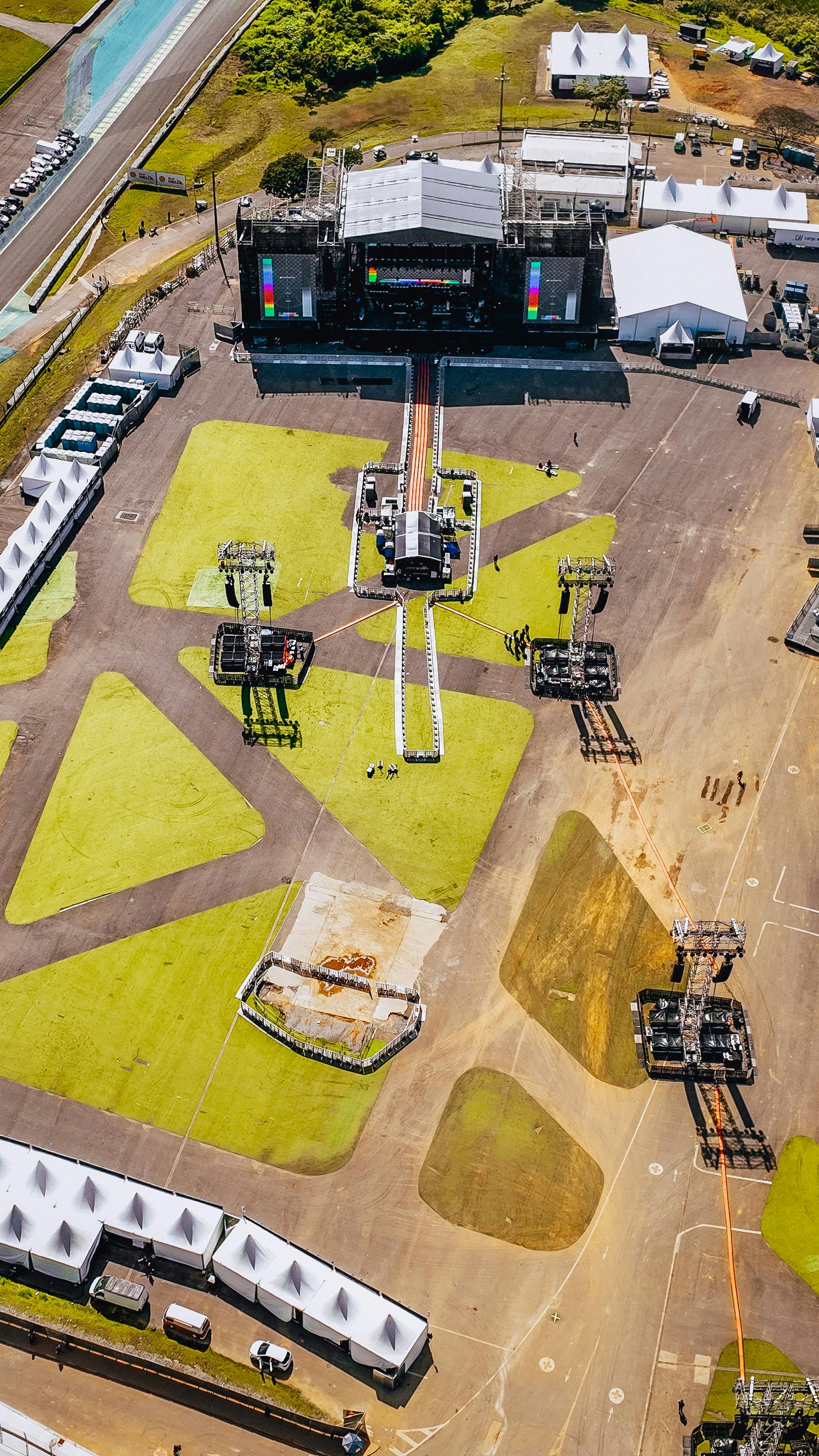 Aerial view of a large outdoor concert stage being set up in a sunny location.