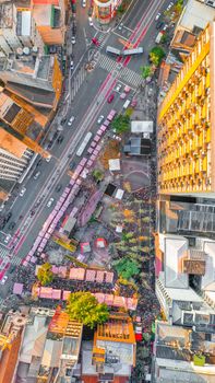 A bustling city scene from above, showcasing a vibrant intersection surrounded by tall buildings and green spaces.