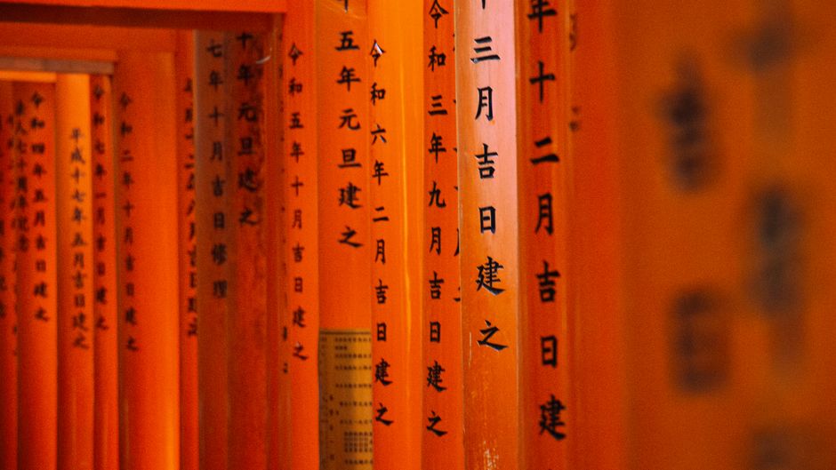 Detailed view of torii gates with Japanese inscriptions at Fushimi Inari Shrine, Kyoto.