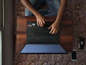 Top View of Person Using Laptop on Wooden Table