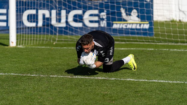 Goalkeeper in action during a football match, making a save on the field.