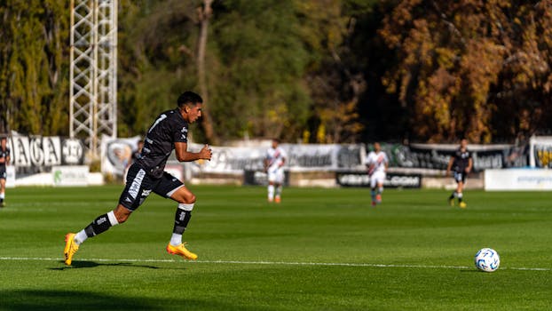 Soccer player sprints towards the ball on a sunny day match.