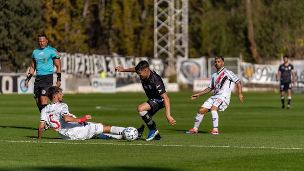 Dynamic action during a football match, capturing the intensity of the game on a sunny day.