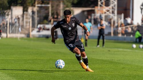 Free Football player in black jersey dribbles ball on a sunny day match. Stock Photo