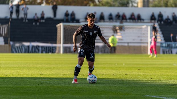 A football player focuses on the ball during an outdoor match on a sunny day.