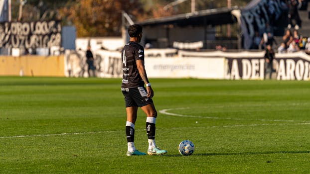 A soccer player in action during a match on a sunny day, ready to make a move.
