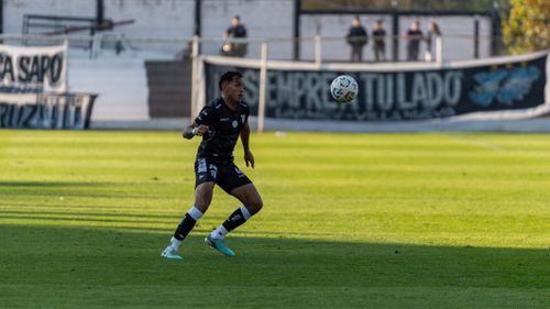 Free Energetic soccer player in black kit focused on the ball during an outdoor match. Stock Photo