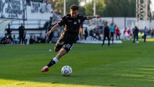 Dynamic action shot of a footballer kicking the ball on the field during a match.