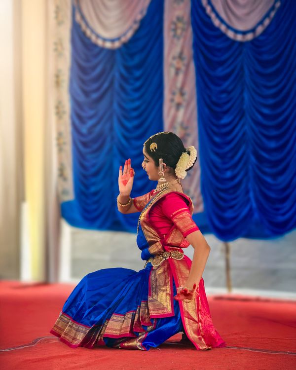 Woman in vibrant saree performing Indian classical dance on stage