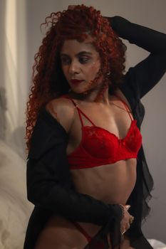 Stylish portrait of a woman in red lace lingerie and black robe, exuding confidence.
