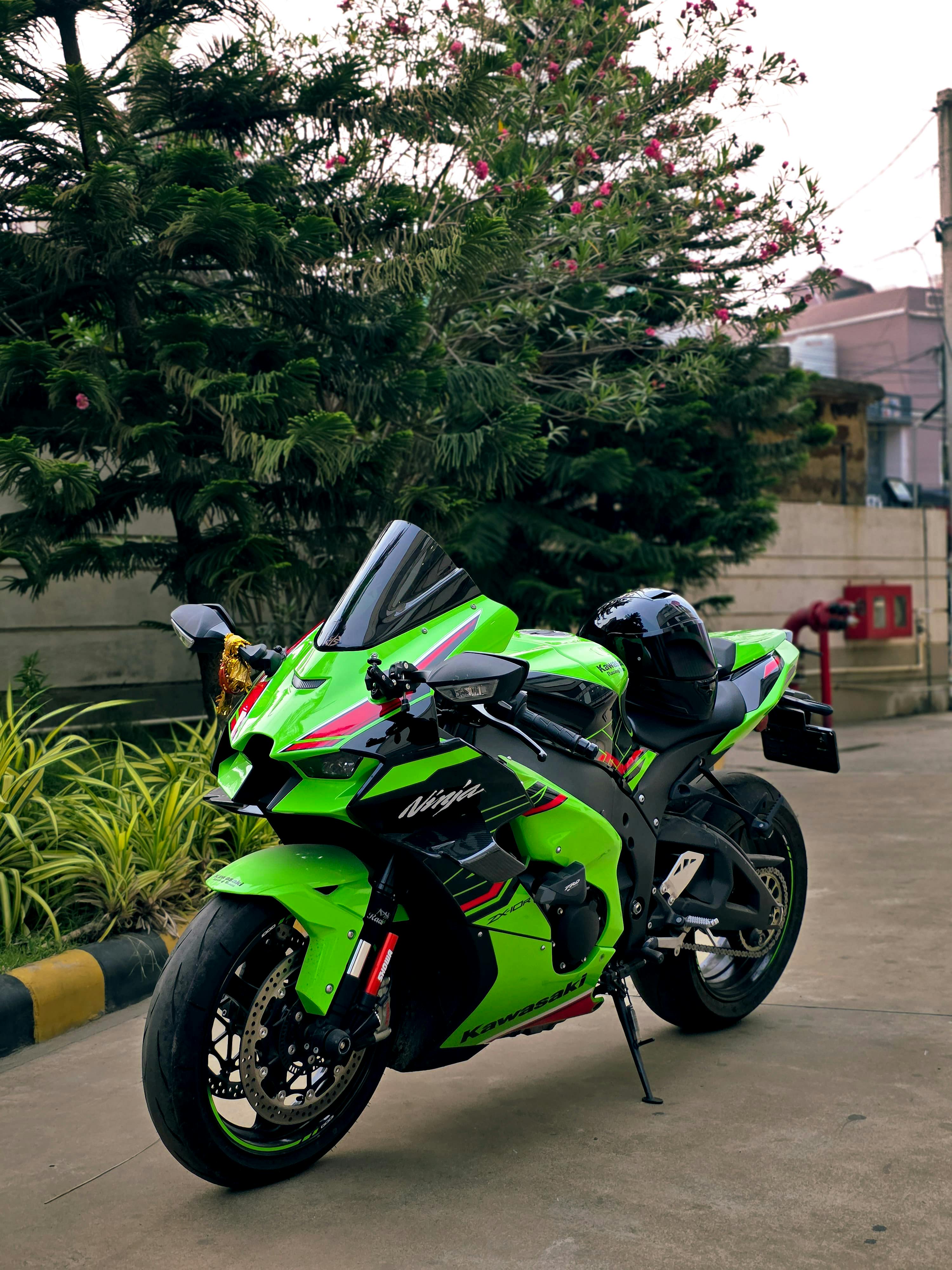 Free Bright green Kawasaki motorcycle parked outdoors in Bhubaneswar with lush greenery in the background, creating a striking scene. Stock Photo
