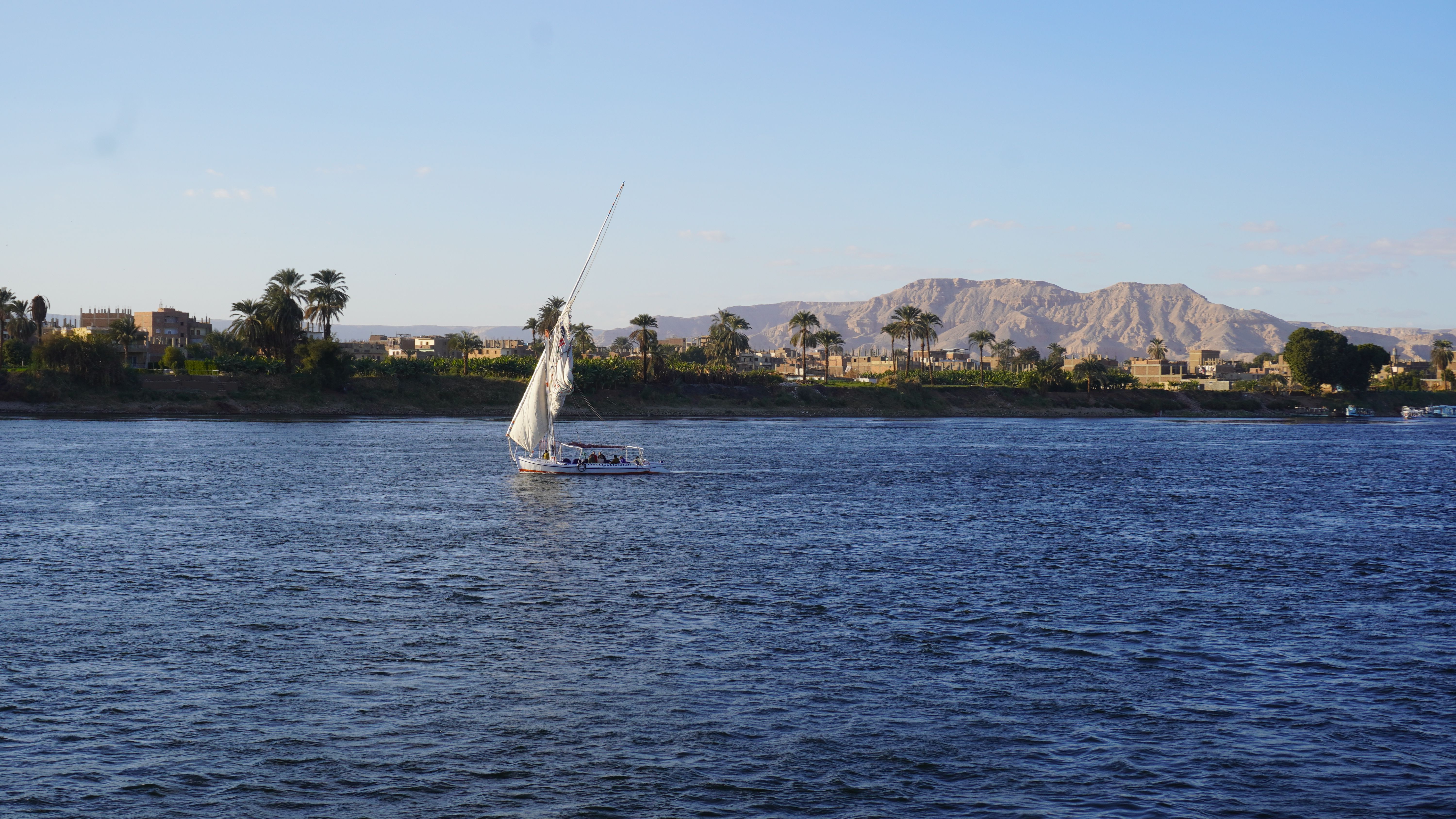Corniche promenade along the Nile with feluccas and hotels on the East Bank of Luxor