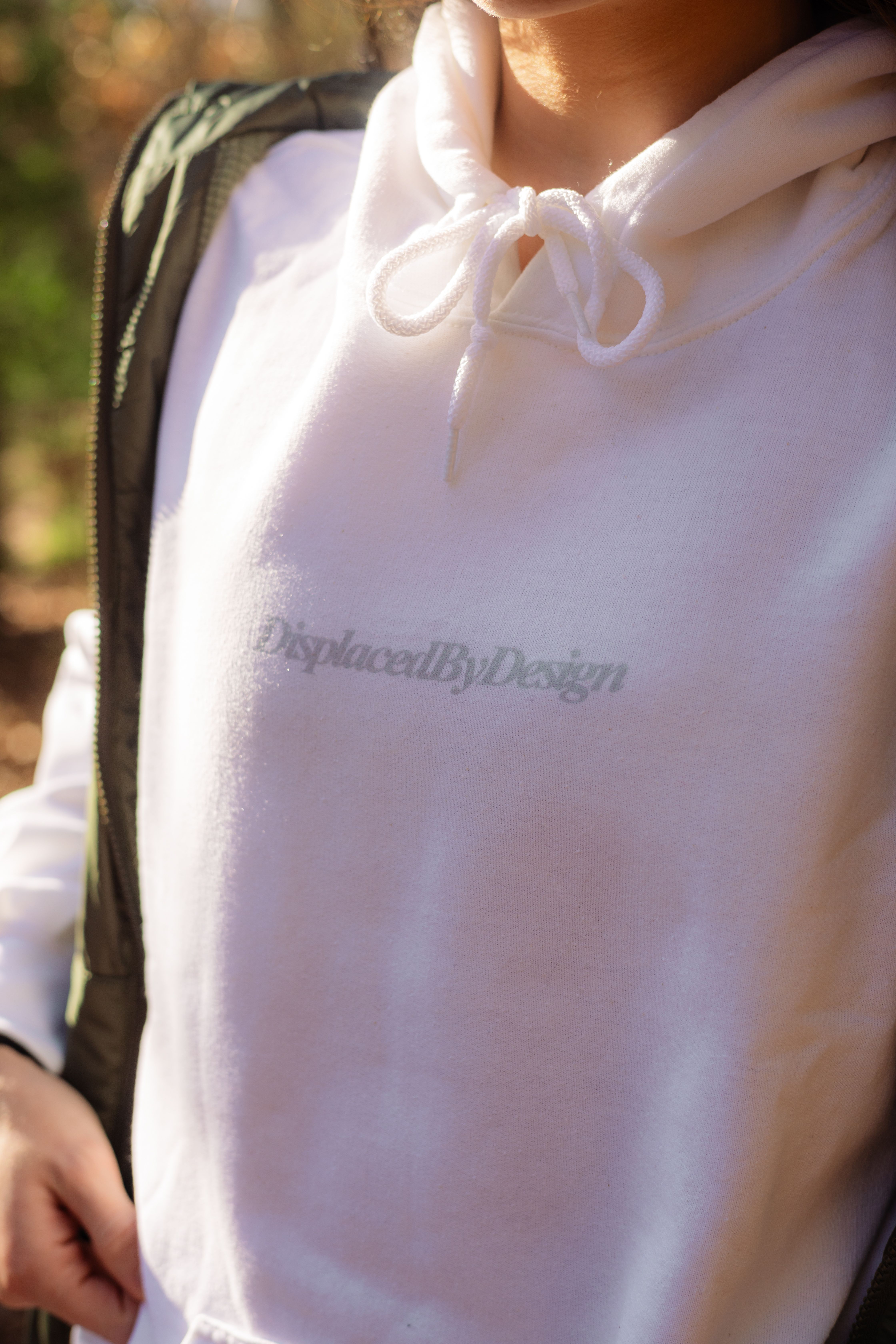Close-up of a white hoodie with text design outdoors in natural light.