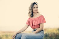 一位身着粉色上衣、面带微笑的女子，正在户外享受阳光明媚的一天