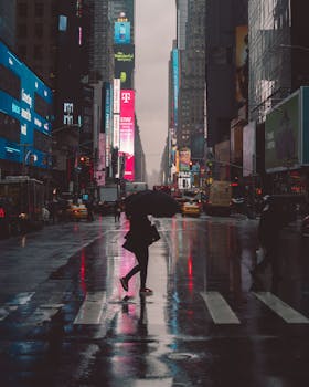 一个人打着伞穿过霓虹灯闪烁的时代广场