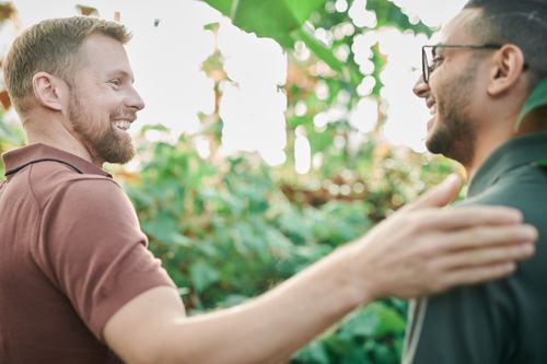 Free Two men enjoying a friendly and happy moment in a lush green environment. Stock Photo