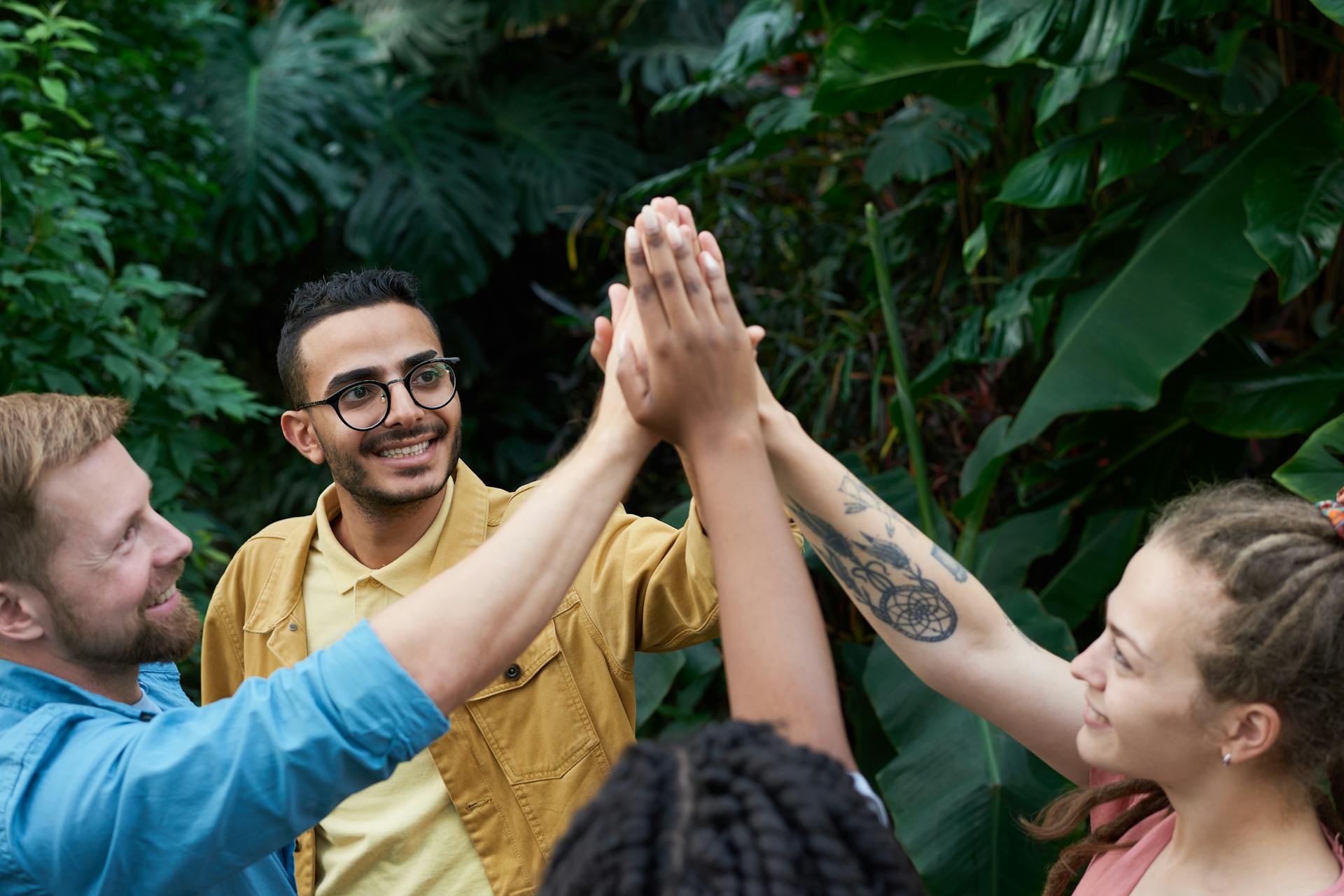 A group of diverse adults high-fiving in an outdoor setting, showcasing teamwork and unity.