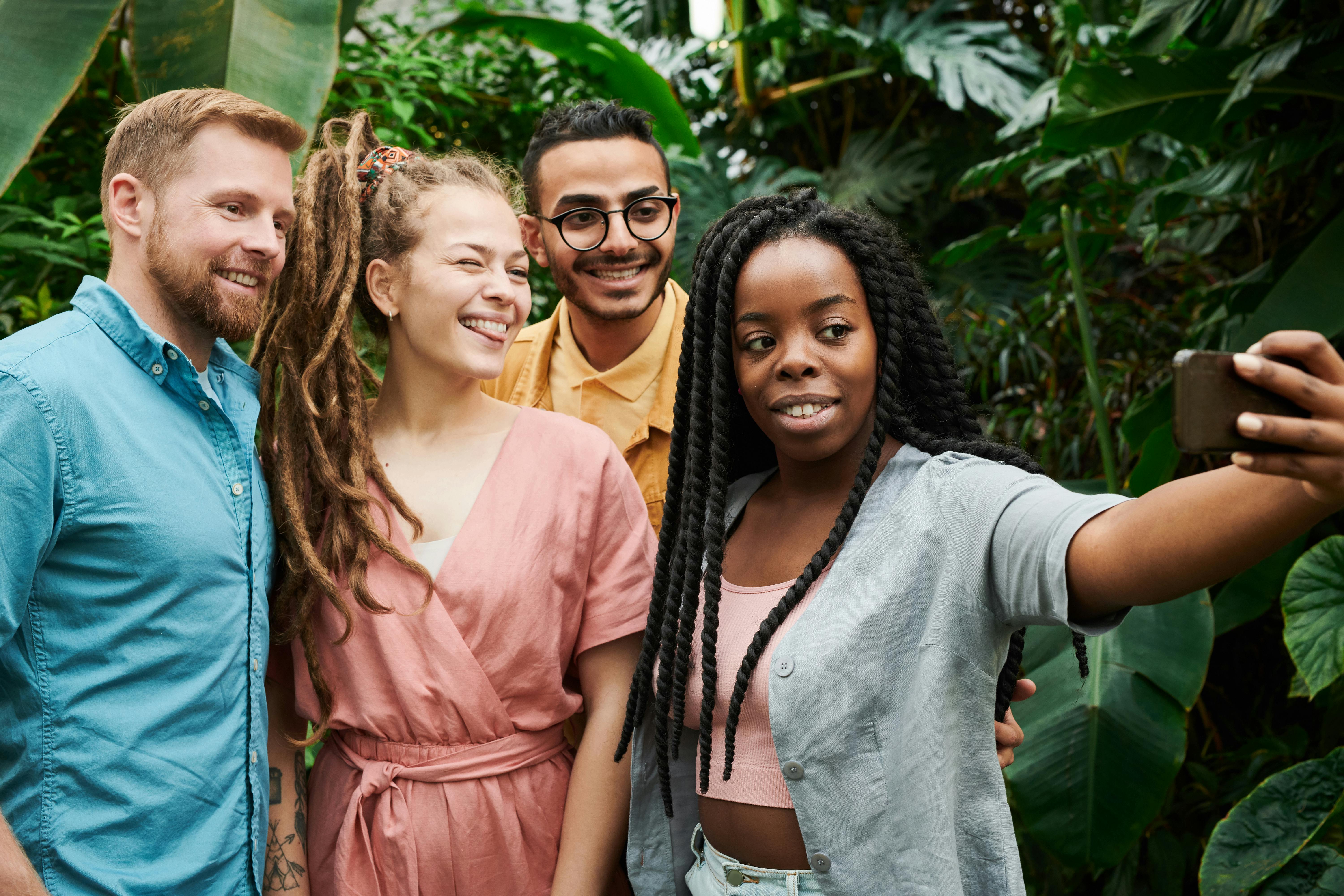 four people taking picture beside plants