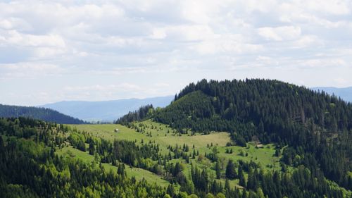 Free Beautiful mountain landscape with lush greenery and a small hut under a cloudy sky. Stock Photo