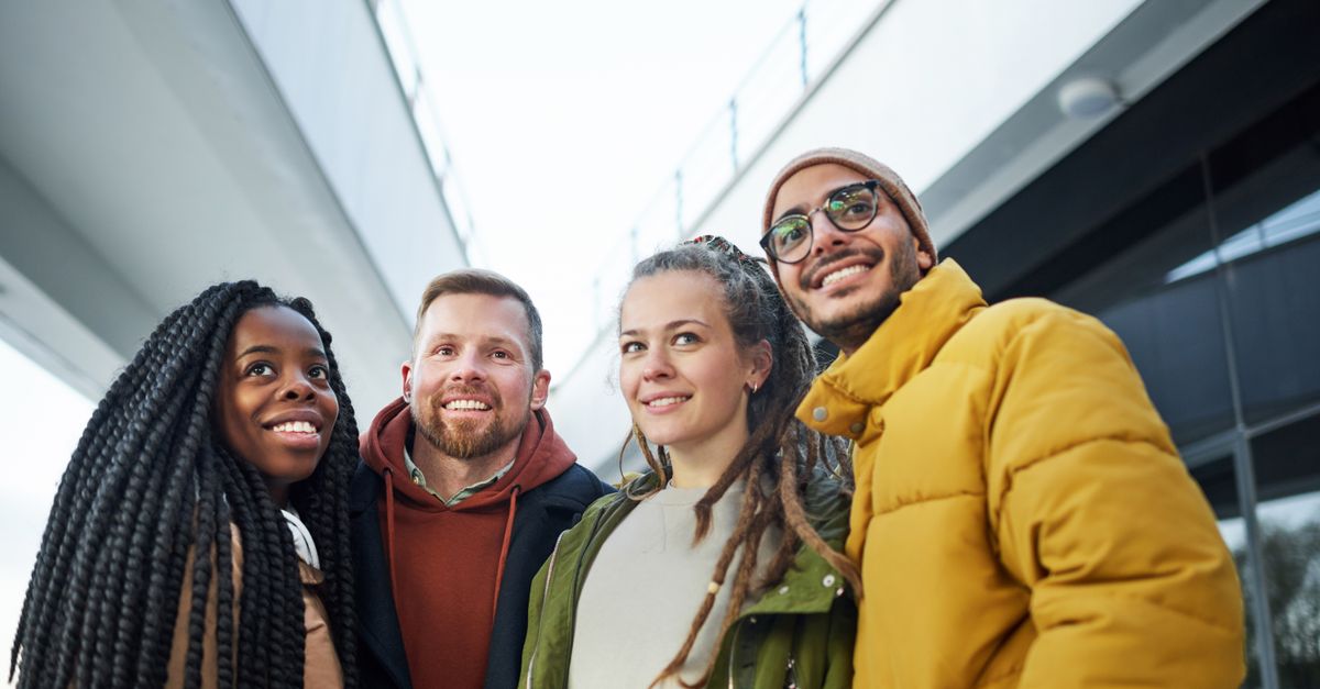A group of diverse, smiling people chatting and laughing together outside a modern church building