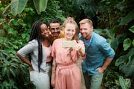 四个朋友在郁郁葱葱的草地上微笑自拍，捕捉户外欢乐时光