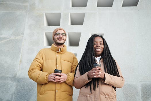 两个朋友穿着冬季夹克，在户外愉快地喝着咖啡