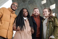 朋友们穿着温暖的冬装，在户外对着镜头微笑，享受冬日时光