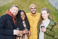 一群朋友在户外微笑着，端着咖啡，拥抱友谊与温暖，他们来自多元的背景