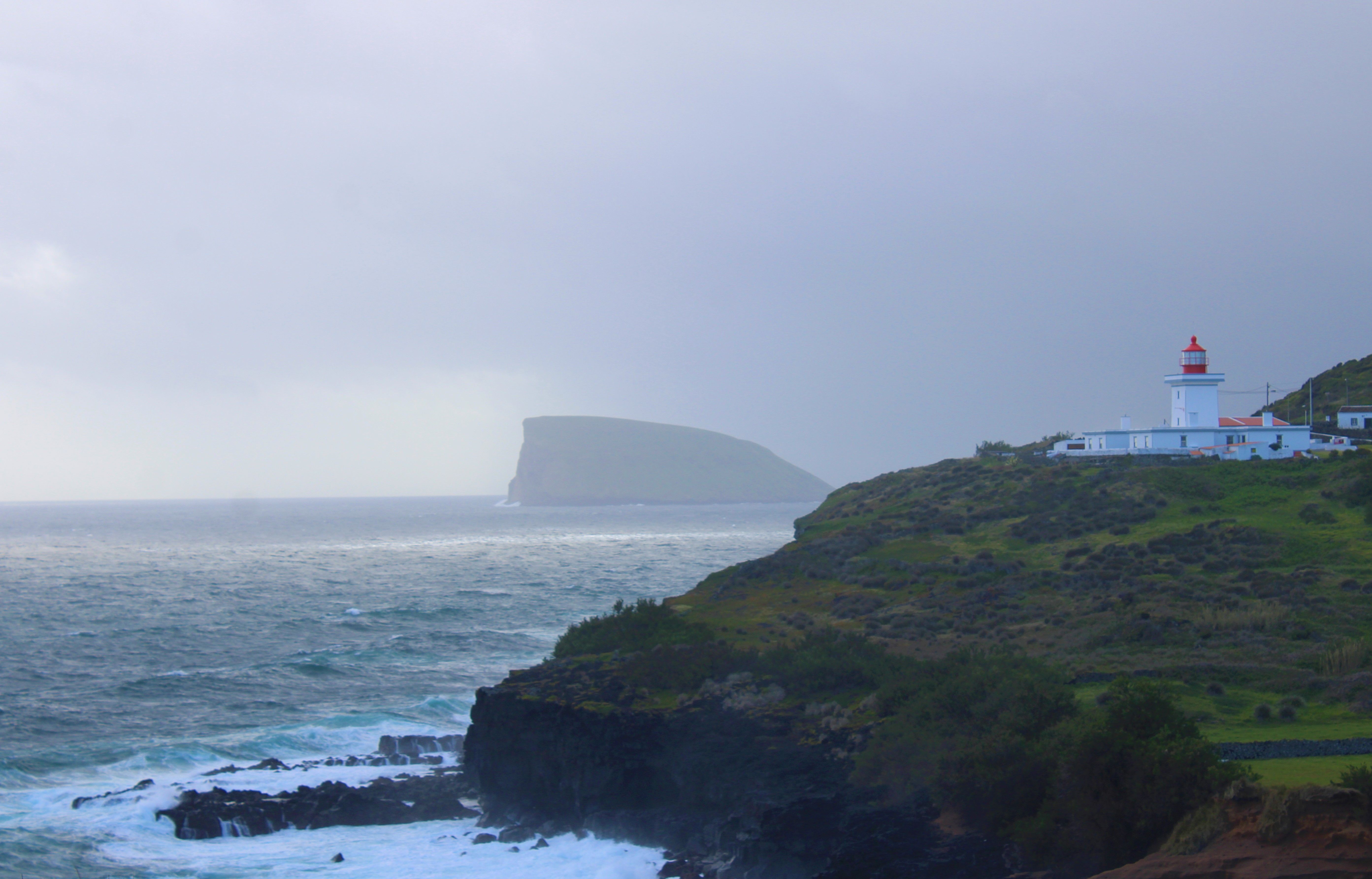 Stunning view of an Azorean lighthouse on a cliffside overlooking the Atlantic Ocean.