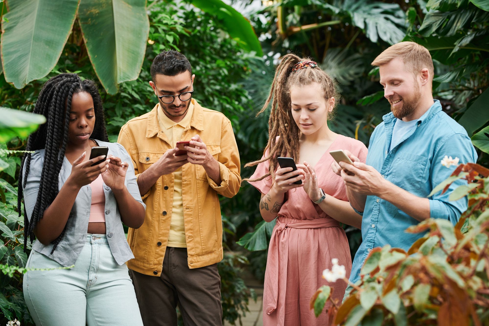 Grupo de amigos jóvenes reunidos al aire libre mirando la pantalla de un teléfono