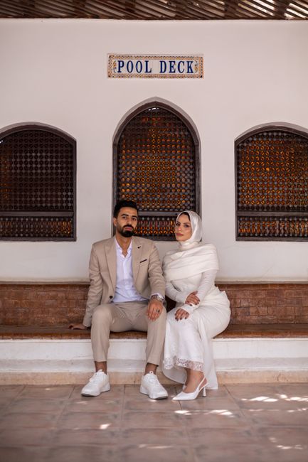 Stylish couple in elegant attire seated at a pool deck, showcasing modern fashion.