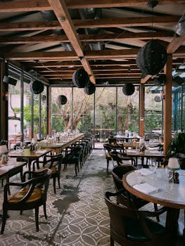 Elegant restaurant with stylish decor, wooden beams and outdoor view.