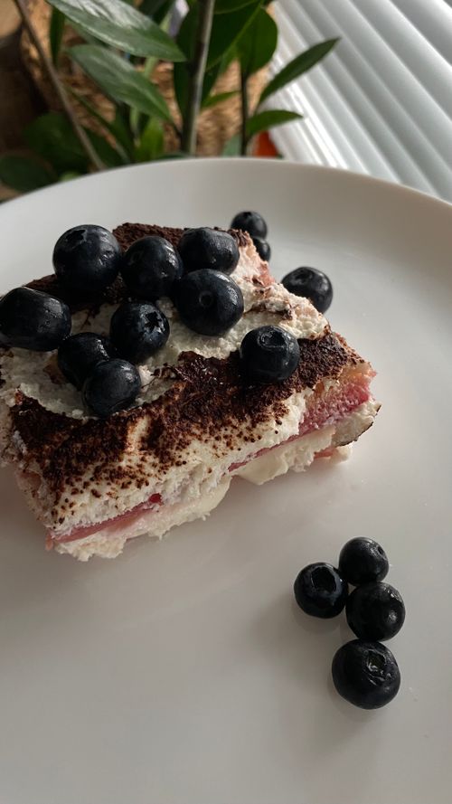 Free Homemade tiramisu topped with fresh blueberries on a white plate. Stock Photo
