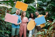 一群朋友在郁郁葱葱的温室里举着色彩缤纷的标语，上面写着演讲内容