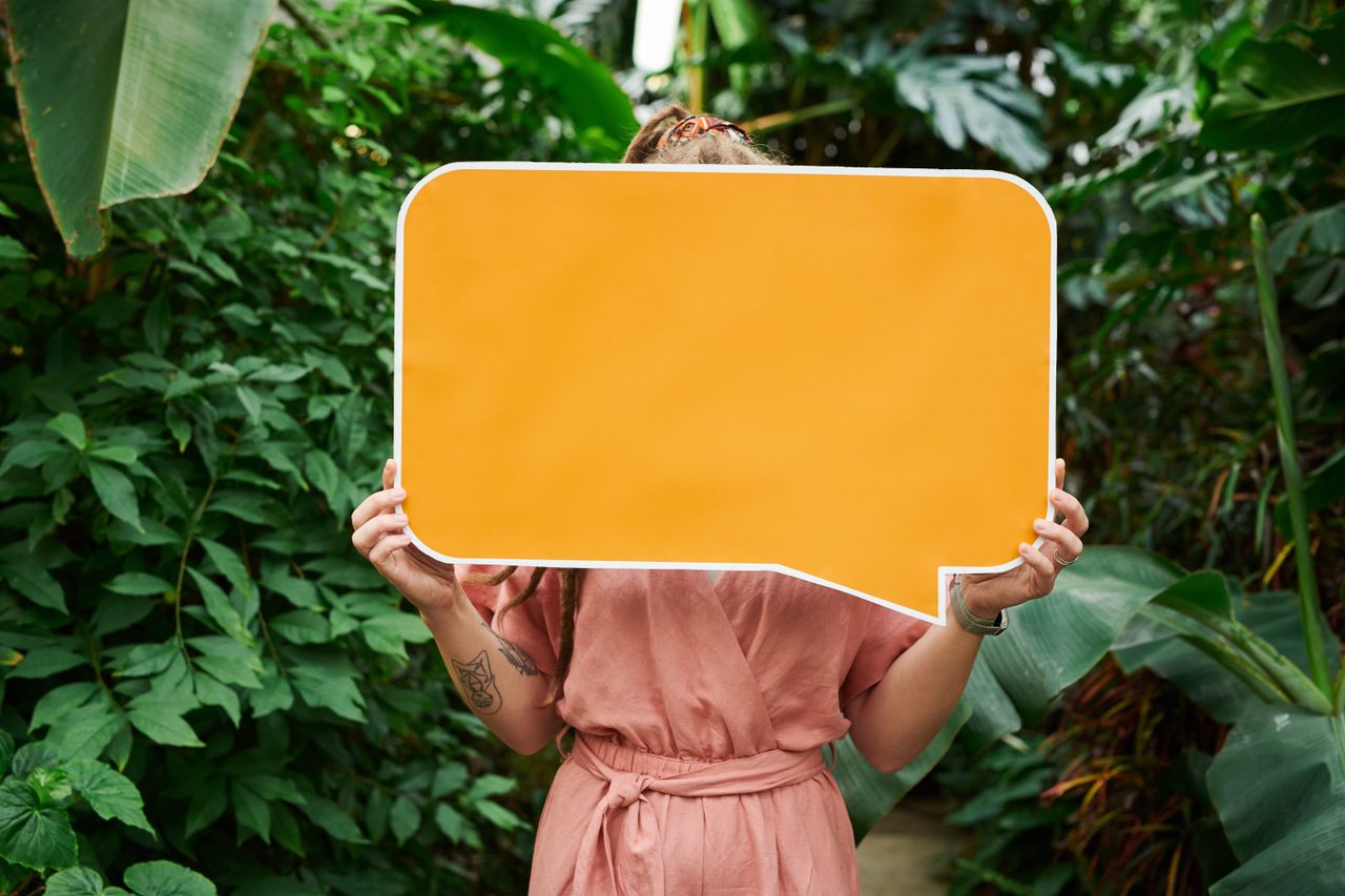 a woman holds an orange blank sign in a tropical garden perfect for cu