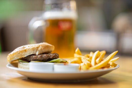 Appetizing cheeseburger with fries and a glass of beer on a wooden table.
