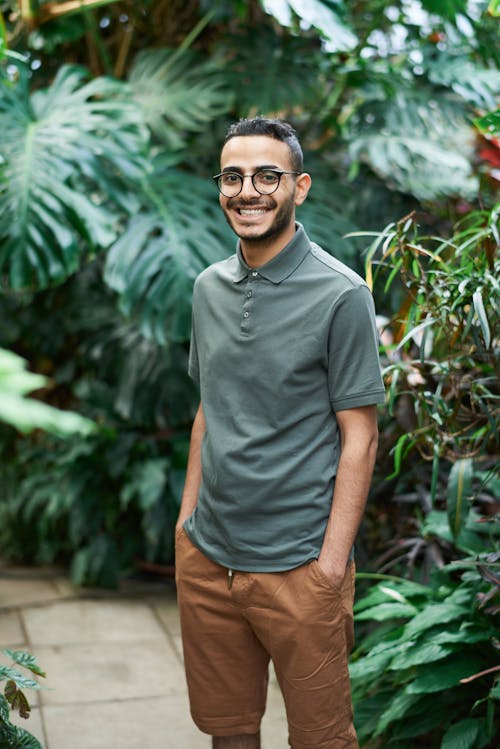 Photo of Man Smiling While Standing Near Plants