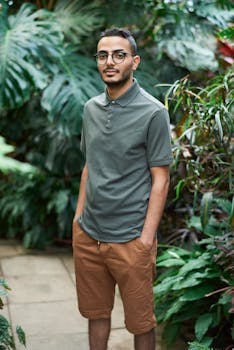 一位穿着休闲装的时尚男士，自信而时尚地站在充满活力的热带植物丛中