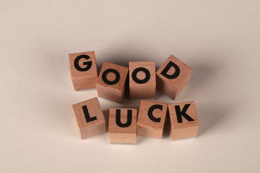 Wooden blocks with letters spell 'Good Luck' on a beige background, signifying encouragement and support.