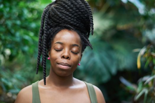 Portrait of a woman with braided hair relaxing outdoors with eyes closed.