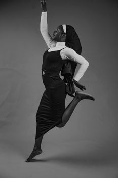 Black and white photo of a person in mid-air dance pose, expressing grace.